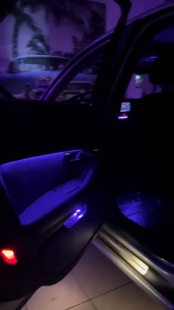 Interior de mașină luminat ambiental în mov, cu portiera deschisă